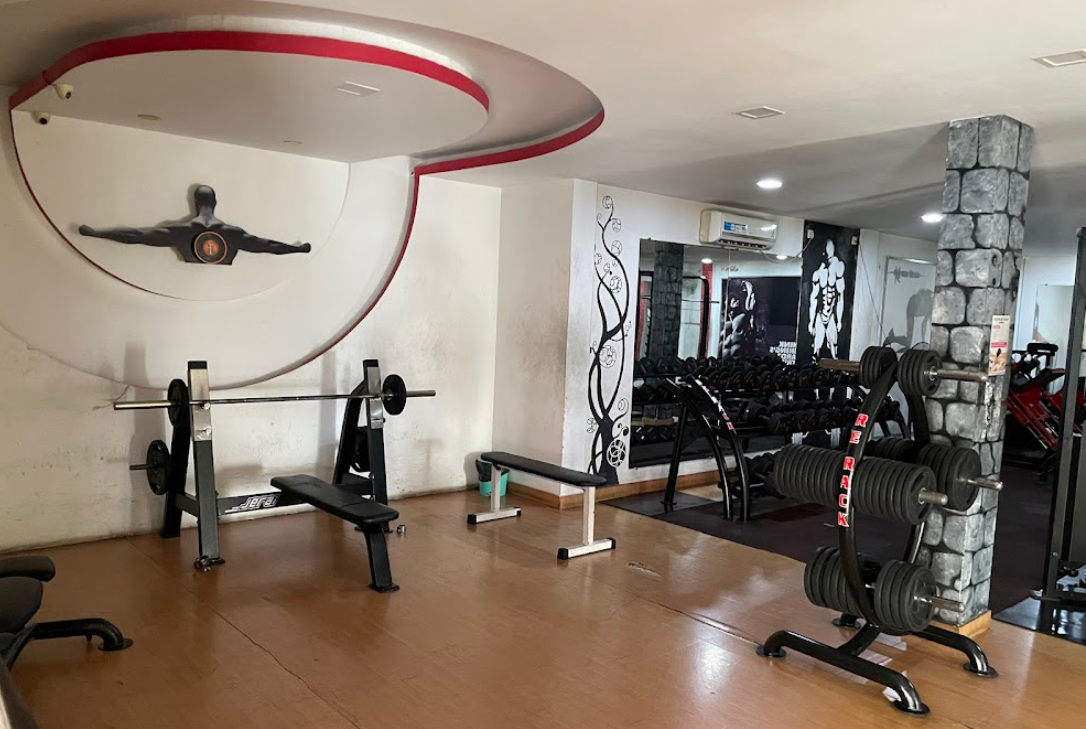Goldstar Fitness : Wide angle of a commercial gym floor featuring rows of strength machines and open floor space.