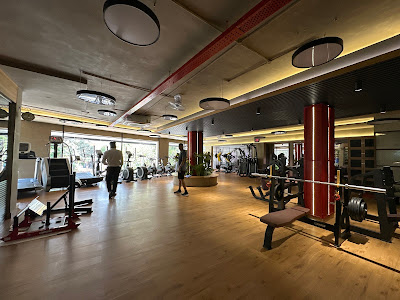 Spacious gym interior with wooden floor, cardio machines, and weight training equipment