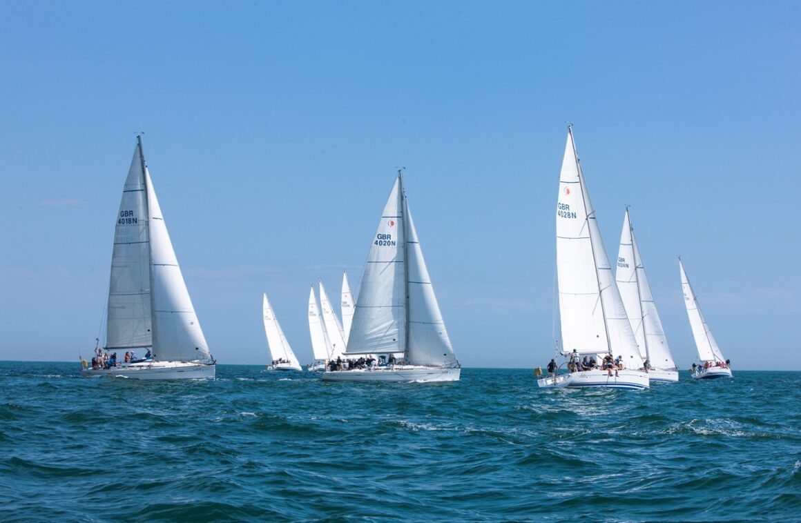 A high-tech America's Cup foiling yacht sailing at speed, showcasing one of the most expensive sports ever in water.